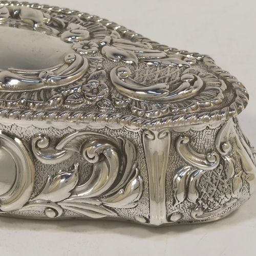 A very pretty Antique Edwardian Sterling Silver Art Nouveau style table box, having a lozenge shaped oval body with a gold-gilt interior hand-chased floral and scroll decoration, a hinged lid with a vacant central oval cartouche, and sitting on a flat base. This beautiful antique silver box was made by John Thompson of Birmingham in 1902. The dimensions of this fine hand-made antique silver Art Nouveau style box are length 13.5 cms (5.25 inches), width 6 cms (2.3 inches), height 4 cms (1.5 inches), and it weighs approx. 88g (2.8 troy ounces).  