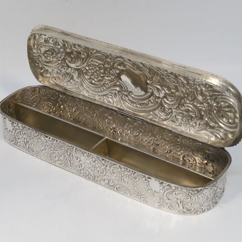 A bold and very pretty Antique Edwardian Sterling Silver table box, having a rounded rectangular body with hand-chased floral and scroll decoration, a hinged lid with matching decoration surrounding a vacant central cartouche, an applied rope-twist top border, a gold-gilt interior with three compartments, and sitting on a flat base. This beautiful silver dressing table box was made by Charles Boyton of Birmingham in 1904. The dimensions of this fine hand-made antique silver table box are length 22 cms (8.75 inches), width 6.5 cms (2.5 inches), height 4 cms (1.5 inches), and it weighs approx. 269g (8.7 troy ounces).