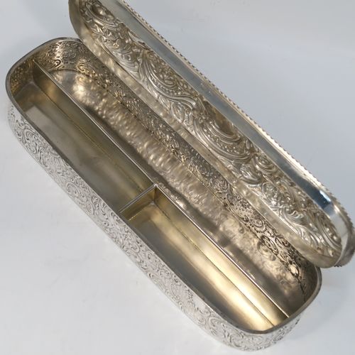 A bold and very pretty Antique Edwardian Sterling Silver table box, having a rounded rectangular body with hand-chased floral and scroll decoration, a hinged lid with matching decoration surrounding a vacant central cartouche, an applied rope-twist top border, a gold-gilt interior with three compartments, and sitting on a flat base. This beautiful silver dressing table box was made by Charles Boyton of Birmingham in 1904. The dimensions of this fine hand-made antique silver table box are length 22 cms (8.75 inches), width 6.5 cms (2.5 inches), height 4 cms (1.5 inches), and it weighs approx. 269g (8.7 troy ounces).
