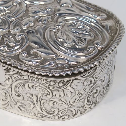 A bold and very pretty Antique Edwardian Sterling Silver table box, having a rounded rectangular body with hand-chased floral and scroll decoration, a hinged lid with matching decoration surrounding a vacant central cartouche, an applied rope-twist top border, a gold-gilt interior with three compartments, and sitting on a flat base. This beautiful silver dressing table box was made by Charles Boyton of Birmingham in 1904. The dimensions of this fine hand-made antique silver table box are length 22 cms (8.75 inches), width 6.5 cms (2.5 inches), height 4 cms (1.5 inches), and it weighs approx. 269g (8.7 troy ounces).