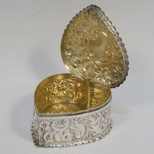 A very pretty Antique Victorian Sterling Silver heart-shaped table box, having a gold-gilt interior, all hand-chased with floral and scroll-work, a hinged lid with vacant cartouche, and all sitting on a flat base. This beautiful silver box was made by Deakin and Francis of Birmingham in 1893. The dimensions of this fine hand-made antique silver hear-shaped box are length 9 cms (3.5 inches), width 8 cms (3.25 inches), height 5 cms (2 inches), and it weighs approx. 96g (3 troy ounces).   