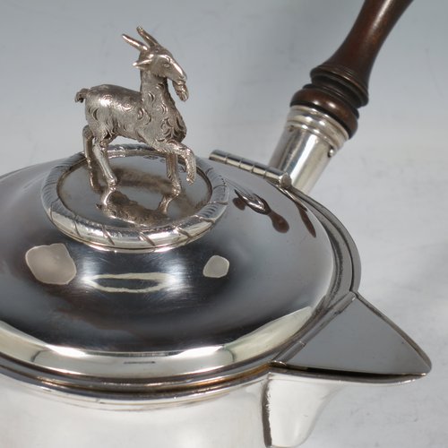 An Antique Georgian Sterling Silver brandy saucepan warmer, having a plain round tapering straight-sided body, a hinged domed lid with a cast goat finial and a hinged sparrow-beak spout, an original wood turned handle, with a gold-gilt interior, and all sitting on a reeded collet foot. Made by Joseph Angell I of London in 1821. The dimensions of this fine hand-made brandy saucepan warmer are height (inc. finial) 13 cms (5 inches), length (inc. handle) 22 cms (8.75 inches), and it weighs approx. 310g (10 troy ounces).