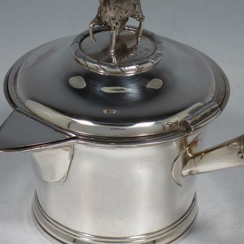 An Antique Georgian Sterling Silver brandy saucepan warmer, having a plain round tapering straight-sided body, a hinged domed lid with a cast goat finial and a hinged sparrow-beak spout, an original wood turned handle, with a gold-gilt interior, and all sitting on a reeded collet foot. Made by Joseph Angell I of London in 1821. The dimensions of this fine hand-made brandy saucepan warmer are height (inc. finial) 13 cms (5 inches), length (inc. handle) 22 cms (8.75 inches), and it weighs approx. 310g (10 troy ounces).
