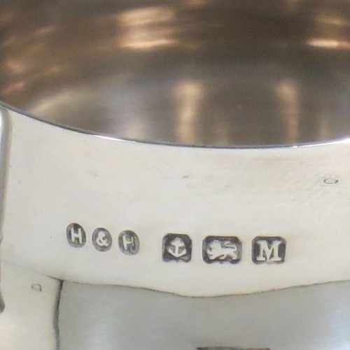 A Sterling Silver brandy saucepan warmer on burner stand, having a plain round baluster body, a sparrow-beak spout, an original wood turned handle, and sitting on a wire-work frame with integral spirit burner. Made by Hukin & Heath of Birmingham in 1936. The dimensions of this fine hand-made silver brandy warmer are height 8 cms (3.25 inches), length (inc. handle) 12 cms (4.75 inches), and it weighs approx. 105g (3.4 troy ounces).