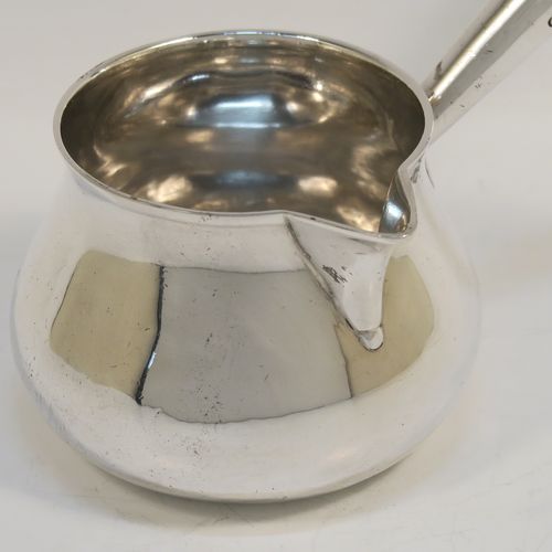 A handsome Antique Georgian Sterling Silver brandy saucepan warmer, having a plain round bellied body, a sparrow-beak spout, an original wood turned handle, and sitting on a flat base. This elegant antique silver brandy or sauce warmer was made by Thomas Oliphant of London in 1801. The dimensions of this fine hand-made silver sauce or brandy warmer are height (inc. handle) 15 cms (6 inches), length (inc. handle) 19 cms (7.5 inches), diameter of main body 9 cms (3.5 inches), and it weighs approx. 150g (4.8 troy ounces).