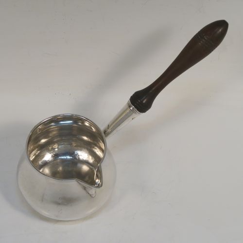 A handsome Antique Georgian Sterling Silver brandy saucepan warmer, having a plain round bellied body, a sparrow-beak spout, an original wood turned handle, and sitting on a flat base. This elegant antique silver brandy or sauce warmer was made by Thomas Oliphant of London in 1801. The dimensions of this fine hand-made silver sauce or brandy warmer are height (inc. handle) 15 cms (6 inches), length (inc. handle) 19 cms (7.5 inches), diameter of main body 9 cms (3.5 inches), and it weighs approx. 150g (4.8 troy ounces).