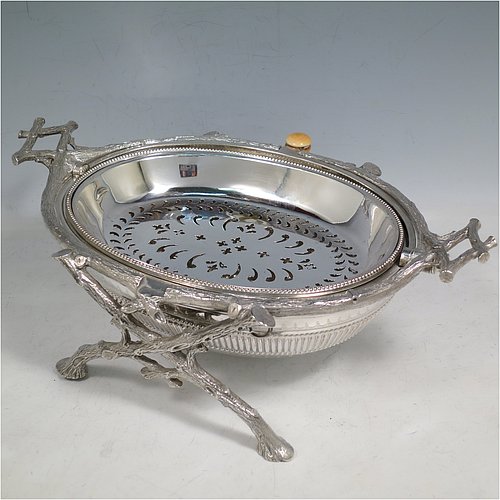 An Antique Victorian Silver Plated breakfast dish with revolving lid, and two original internal liners, having a hand-chased body with a fluted band and original bone button, all sitting in a cast frame with legs designed to look like naturalistic wooden branches. Made by the Fenton Brothers of Sheffield in ca. 1870. The dimensions of this fine hand-made antique silver-plated breakfast revolving serving dish are height 16.6 cms (6.5 inches), length 29 cms (11.5 inches), width 20 cms (8 inches).