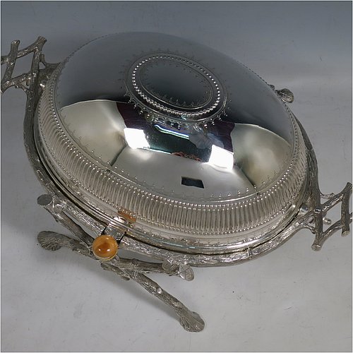 An Antique Victorian Silver Plated breakfast dish with revolving lid, and two original internal liners, having a hand-chased body with a fluted band and original bone button, all sitting in a cast frame with legs designed to look like naturalistic wooden branches. Made by the Fenton Brothers of Sheffield in ca. 1870. The dimensions of this fine hand-made antique silver-plated breakfast revolving serving dish are height 16.6 cms (6.5 inches), length 29 cms (11.5 inches), width 20 cms (8 inches).