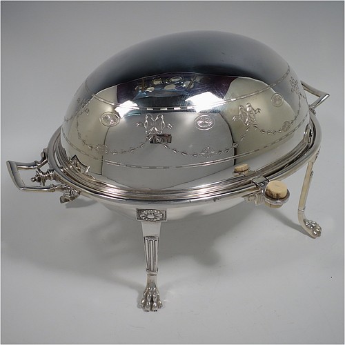 A very pretty Antique Victorian Silver Plated oval breakfast dish with revolving lid, and two original internal liners, having a hand-engraved body with neoclassical style bows and swags, an original bone insulated button, all sitting in a cast frame with fluted legs on lions-paw feet. Made in Sheffield in ca. 1890. The dimensions of this fine hand-made antique silver-plated breakfast revolving serving dish are height 20 cms (8 inches), length 34 cms (13.5 inches), width 23 cms (9 inches).    