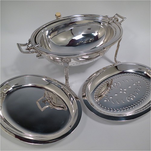 A very pretty Antique Victorian Silver Plated oval breakfast dish with revolving lid, and two original internal liners, having a hand-engraved body with neoclassical style bows and swags, an original bone insulated button, all sitting in a cast frame with fluted legs on lions-paw feet. Made in Sheffield in ca. 1890. The dimensions of this fine hand-made antique silver-plated breakfast revolving serving dish are height 20 cms (8 inches), length 34 cms (13.5 inches), width 23 cms (9 inches).