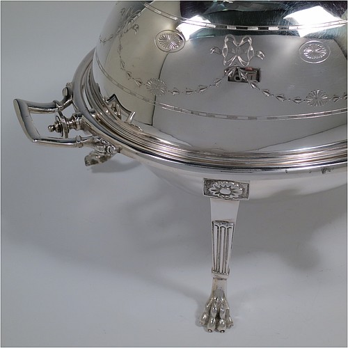 A very pretty Antique Victorian Silver Plated oval breakfast dish with revolving lid, and two original internal liners, having a hand-engraved body with neoclassical style bows and swags, an original bone insulated button, all sitting in a cast frame with fluted legs on lions-paw feet. Made in Sheffield in ca. 1890. The dimensions of this fine hand-made antique silver-plated breakfast revolving serving dish are height 20 cms (8 inches), length 34 cms (13.5 inches), width 23 cms (9 inches).
