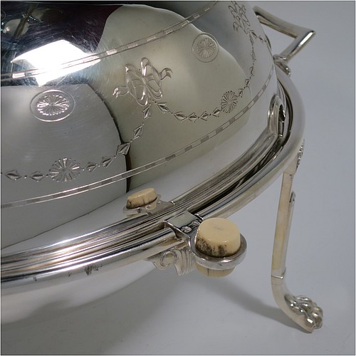 A very pretty Antique Victorian Silver Plated oval breakfast dish with revolving lid, and two original internal liners, having a hand-engraved body with neoclassical style bows and swags, an original bone insulated button, all sitting in a cast frame with fluted legs on lions-paw feet. Made in Sheffield in ca. 1890. The dimensions of this fine hand-made antique silver-plated breakfast revolving serving dish are height 20 cms (8 inches), length 34 cms (13.5 inches), width 23 cms (9 inches).