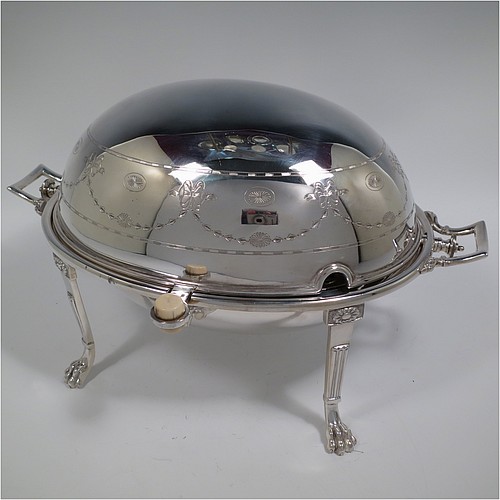 A very pretty Antique Victorian Silver Plated oval breakfast dish with revolving lid, and two original internal liners, having a hand-engraved body with neoclassical style bows and swags, an original bone insulated button, all sitting in a cast frame with fluted legs on lions-paw feet. Made in Sheffield in ca. 1890. The dimensions of this fine hand-made antique silver-plated breakfast revolving serving dish are height 20 cms (8 inches), length 34 cms (13.5 inches), width 23 cms (9 inches).