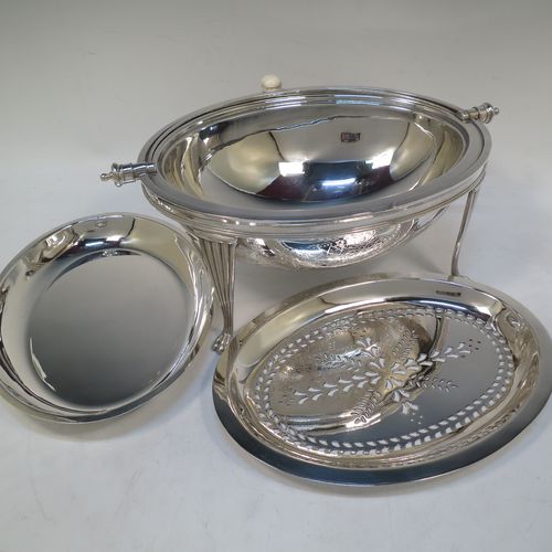 A very pretty Antique Victorian Silver Plated oval breakfast dish with revolving lid, and two original internal liners, having a hand-engraved body with floral and scroll decoration, an original bone insulated button, all sitting in a cast frame with fluted legs on lions-paw feet. Made by Mappin and Webb of Sheffield in ca. 1890. The dimensions of this fine hand-made antique silver-plated breakfast revolving serving dish are height 22 cms (8.5 inches), length 34 cms (13.5 inches), width 23 cms (9 inches).