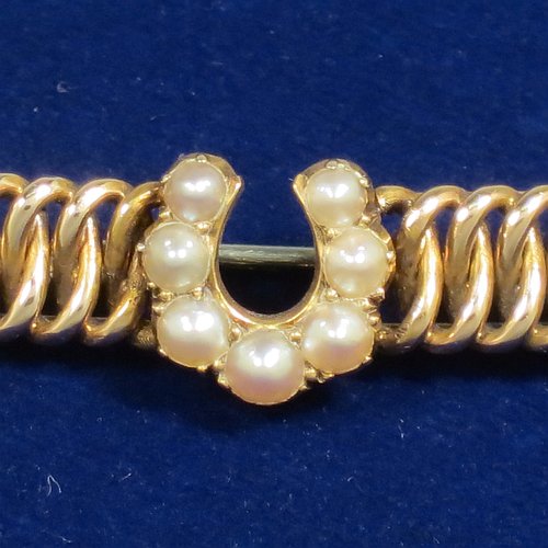 An Antique Victorian 15ct carat gold bar brooch, with the front having seven old pearls applied as a horse-shoe shape sitting on an inter-twined looped body, and the back having a plain steel security pin. Made in ca. 1880. The dimensions of this fine antique gold bar brooch are length 3.5 cms (1.3 inches), width 4 cms (1.5 inch), and it weighs approx. 4g.