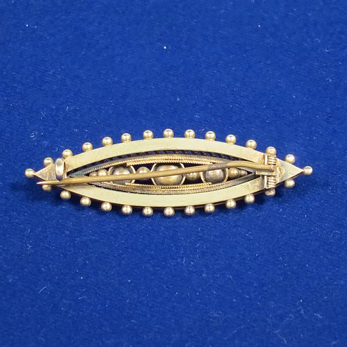 An Antique Victorian Etruscan style 15ct carat gold brooch, having an elongated oval body, with applied bead decoration, and a centre with three old graduated pearls, and the back having a security pin. Made in ca. 1880. The dimensions of this fine antique gold brooch are length 5 cms (2 inches), width 2 cms (0.75 inch), and it weighs approx. 4.8g.