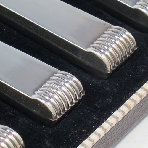A Sterling Silver Art Deco style set of six butter or tea knives, having plain rectangular cross-section handles with reeded terminals, and plain finger-point stainless steel blades, all in their original cream satin and black velvet-lined presentation box. Made by Charles Boyton & Sons of Sheffield in 1939. The dimensions of this fine hand-made set of tea or butter knives are length of each knife 18 cms (7 inches), and the total weight is approx. 120g (4 troy ounces).