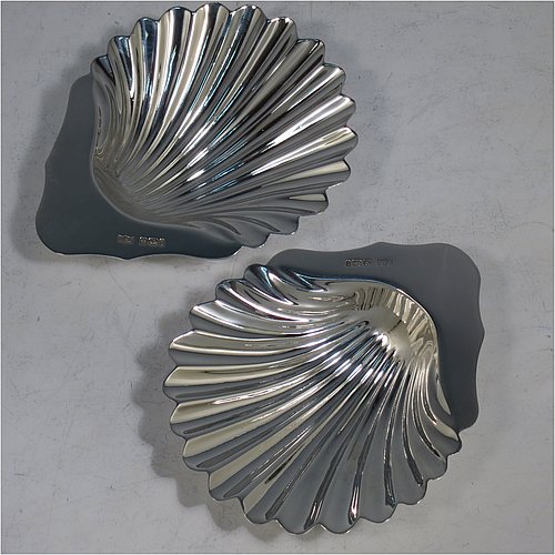 An Antique Victorian Sterling Silver pair of butter shells, having hand-chased scalloped bodies, plain shaped thumb-pieces, and both sitting on three ball feet. All made by Mappin & Webb of Sheffield in 1901. The dimensions of these fine hand-made antique silver butter dishes are length 12 cms (4.75 inches), width 9.5 cms (3.75 inches), height 2 cms (0.75 inches), and they have a total weight of approx. 146g (4.7 troy ounces).