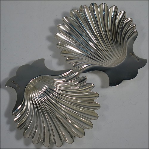 A very handsome Antique Victorian Sterling Silver pair of butter shells, having hand-chased scalloped bodies, plain shaped thumb-pieces, and both sitting on three cast shell-shaped feet. All made by Walker and Hall of Sheffield in 1897/99. The dimensions of these fine hand-made antique silver butter dishes are length 13 cms (5 inches), width 11 cms (4.25 inches), height 2.5 cms (1 inch), and they have a total weight of approx. 163g (5.25 troy ounces).    