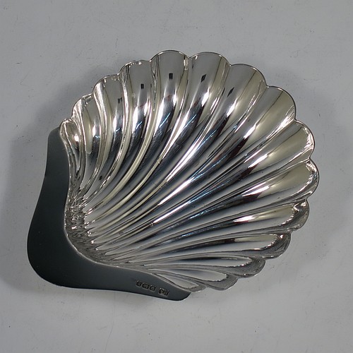 An Antique Sterling Silver pair of butter shells, having hand-chased scalloped bodies, plain shaped thumb-pieces, and both sitting on three ball feet. All made by Henry Atkins of Sheffield in 1913. The dimensions of these fine hand-made antique silver butter dishes are length 12 cms (4.75 inches), width 10 cms (4 inches), height 2.5 cms (1 inch), and they have a total weight of approx. 113g (3.6 troy ounces).