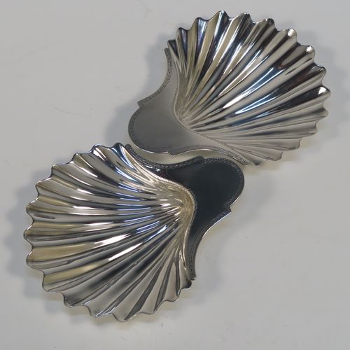 A very handsome pair of Antique Georgian Sterling Silver butter shells, having hand-chased scalloped bodies, shaped thumb-pieces with hand-engraved floral borders, and both sitting on three cast Conch shell-shaped feet. These beautiful antique silver butter shells were made by Hester Bateman of London in 1782. The dimensions of these fine hand-made antique silver butter dish shells are length 15 cms (6 inches), width 12.5 cms (5 inches), and they have a total weight of approx. 211g (6.8 troy ounces).