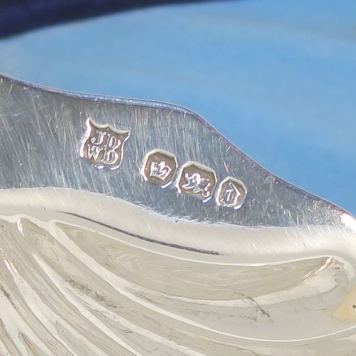 A very handsome Antique Victorian Sterling Silver butter shell and original butter knife, the shell having a hand-chased scalloped body, and sitting on three ball feet, the butter knife in the Old English Shell pattern, and all in their original blue satin and velvet-lined presentation box. Made by John & William Deakin of Sheffield in 1896. The dimensions of this fine hand-made antique silver butter dish and knife are length of dish 10 cms (4 inches), width 8.5 cms (3.25 inches), length of knife 10.5 cms (4.25 inches), and they weigh a total of approx 47g (1.5 troy ounces).