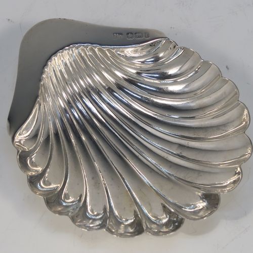 A handsome Antique Edwardian Sterling Silver pair of butter shells, having hand-chased scalloped bodies, plain shaped thumb-pieces, and both sitting on three ball feet. These beautiful silver shell butter dishes were made by Henry Atkins of Sheffield in 1909. The dimensions of these fine hand-made antique silver butter dishes are length 12 cms (4.75 inches), width 10 cms (4 inches), and they have a total weight of approx. 115g (3.7 troy ounces).