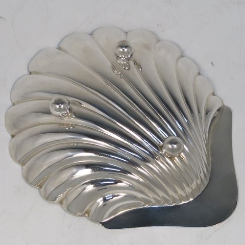 A handsome Antique Edwardian Sterling Silver pair of butter shells, having hand-chased scalloped bodies, plain shaped thumb-pieces, and both sitting on three ball feet. These beautiful silver shell butter dishes were made by Henry Atkins of Sheffield in 1909. The dimensions of these fine hand-made antique silver butter dishes are length 12 cms (4.75 inches), width 10 cms (4 inches), and they have a total weight of approx. 115g (3.7 troy ounces).
