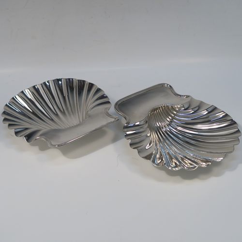 A very handsome pair of Antique early Victorian Sterling Silver butter shells, having hand-chased scalloped bodies, shaped thumb-pieces with applied reeded borders, and both sitting on three cast Conch shell-shaped feet. These beautiful antique silver butter shells were made by Mary and Richard Sibley of London in 1839. The dimensions of these fine hand-made antique silver butter dish shells are length 15 cms (6 inches), width 14 cms (5.5 inches), and they have a total weight of approx. 248g (8 troy ounces).   