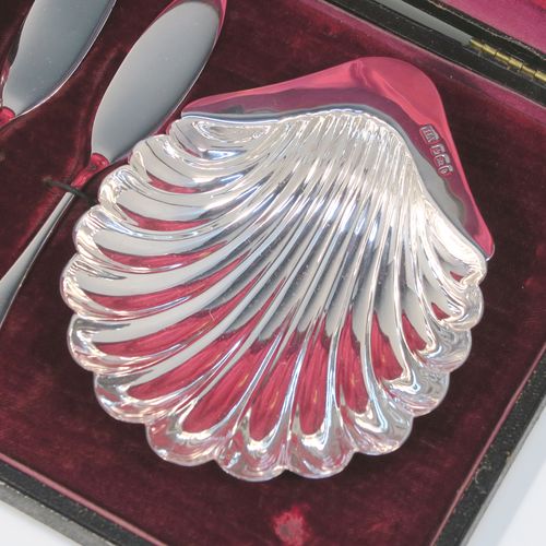 An elegant Antique Victorian Sterling Silver pair of butter shells, having traditional scallop shapes, and sitting on three cast ball feet, together with a pair of original butter knives in the Old English pattern, and all sitting in an original maroon satin and velvet-lined presentation box. This handsome pair of silver butter shells and knives were all made by the Atkin Brothers of Sheffield in 1900. The dimensions of this fine hand-made set of antique silver butter shells and knives are length 12 cms (4.75 inches), width 10 cms (4 inches), with a total weight of approx. 136g (4.4 troy ounces).
