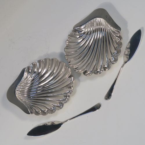 An elegant Antique Victorian Sterling Silver pair of butter shells, having traditional scallop shapes, and sitting on three cast ball feet, together with a pair of original butter knives in the Old English pattern, and all sitting in an original maroon satin and velvet-lined presentation box. This handsome pair of silver butter shells and knives were all made by the Atkin Brothers of Sheffield in 1900. The dimensions of this fine hand-made set of antique silver butter shells and knives are length 12 cms (4.75 inches), width 10 cms (4 inches), with a total weight of approx. 136g (4.4 troy ounces).