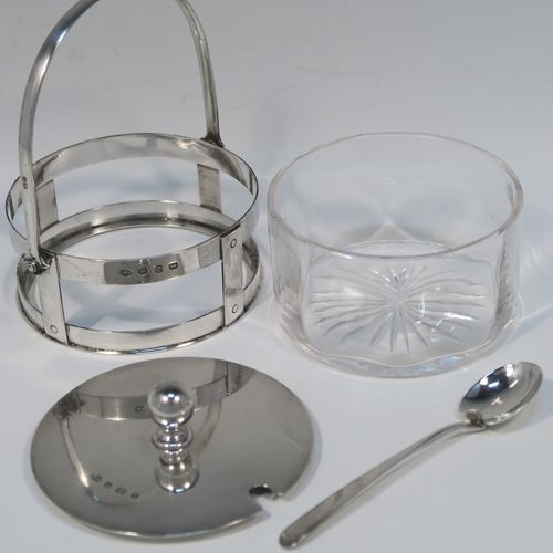 A very unusual Antique Victorian Sterling Silver and crystal butter, jam or honey dish and cover in an Arts and Crafts style, having a plain round galleried body with a hand-cut crystal liner and a swing-handle, a lift-off plain round cover with ball finial, and all sitting in a flat base, together with a matching condiment spoon . This elegant antique silver jam, honey or butter dish and cover was made by Norton and White of Birmingham in 1900. The matching spoon was made in Birmingham in 1906. The dimensions of this fine hand-made antique Arts and Crafts style silver covered dish are diameter 9 cms (3.5 inches), height (inc. handles) 12 cms (4.75 inches), with a total weight of approx. 200g (6.5 troy ounces).