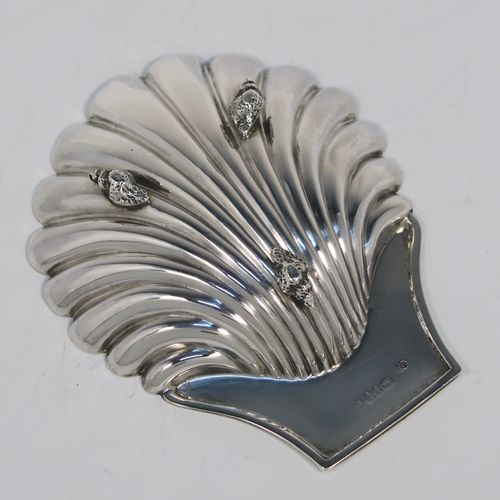 A very handsome Antique Victorian Sterling Silver butter shell dish, having a hand-chased scalloped body, a plain flat side handle, and all sitting on three cast shell feet. This elegant antique silver butter shell was made by Charles Boyton of London in 1886. The dimensions of this fine hand-made antique silver butter dish shell are length 13 cms (5.25 inches), width 10 cms (4 inches), and it weighs approx. 75g (2.4 troy ounces).