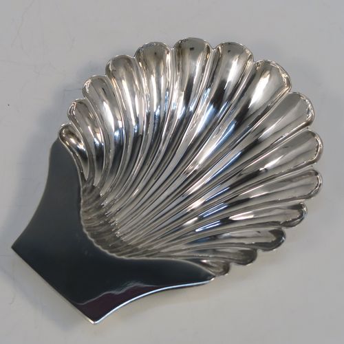 A very handsome Antique Victorian Sterling Silver butter shell dish, having a hand-chased scalloped body, a plain flat side handle, and all sitting on three cast shell feet. This elegant antique silver butter shell was made by Charles Boyton of London in 1886. The dimensions of this fine hand-made antique silver butter dish shell are length 13 cms (5.25 inches), width 10 cms (4 inches), and it weighs approx. 75g (2.4 troy ounces).