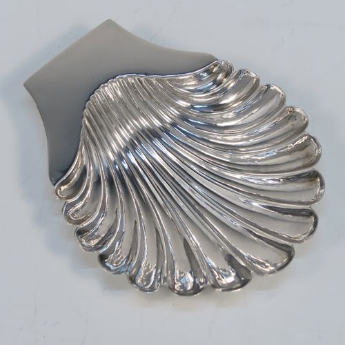 A very handsome Antique Victorian Sterling Silver butter shell dish, having a hand-chased scalloped body, a plain flat side handle, and all sitting on three cast shell feet. This elegant antique silver butter shell was made by Charles Boyton of London in 1886. The dimensions of this fine hand-made antique silver butter dish shell are length 13 cms (5.25 inches), width 10 cms (4 inches), and it weighs approx. 75g (2.4 troy ounces).