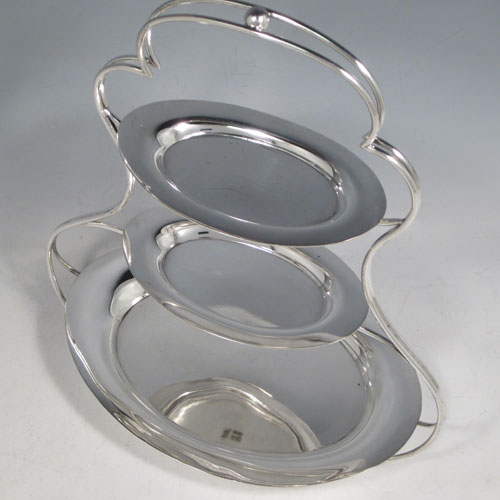 Antique Edwardian Art Nouveau silver plated three-tier cake stand, having a suite of three removable oval plates, sitting within a shaped frame with four cushion feet. Made by George Unite of Birmingham in ca. 1900. The dimensions of this fine hand-made silver-plated cake stand are height 29 cms (11.5 inches), width at base 24 cms (9.5 inches), width of largest plate 21.5 cms (8.5 inches), width of smaller plates 13.5 cms (5.25 inches).