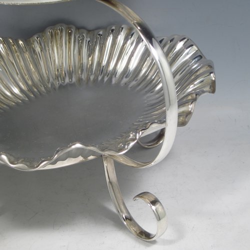 An Antique Victorian Art Nouveau style silver plated three-tier cake stand, having a graduated suite of three removable plates with hand-chased and fluted oval bodies, sitting within a very pretty tapering looped frame with cast shell-work handle and scroll feet. Made by Walker & Hall of Sheffield in ca. 1890. The dimensions of this fine hand-made silver-plated cake stand are height 42 cms (16.3 inches), width of frame at its widest point 25.5 cms (10 inches), and length of largest plate at base 25.5 cms (10 inches).