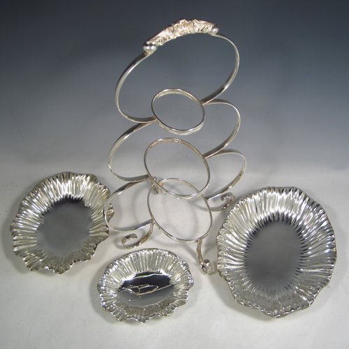 An Antique Victorian Art Nouveau style silver plated three-tier cake stand, having a graduated suite of three removable plates with hand-chased and fluted oval bodies, sitting within a very pretty tapering looped frame with cast shell-work handle and scroll feet. Made by Walker & Hall of Sheffield in ca. 1890. The dimensions of this fine hand-made silver-plated cake stand are height 42 cms (16.3 inches), width of frame at its widest point 25.5 cms (10 inches), and length of largest plate at base 25.5 cms (10 inches).