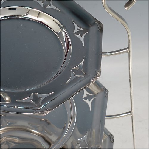 An Antique Edwardian pretty silver-plated cake stand, having three removable and graduated octagonal dishes with hand-pierced borders, all held in a wire-work frame with an oval carrying handle over scroll-work, and sitting on three bun feet. All made in ca. 1900. The dimensions of this fine hand-made antique silver-plated cake stand are height 45 cms (17.75 inches), width 30 cms (11.75 inchs), and the diameter of the dishes vary from 16.5 cms (6.5 inches) to 22 cms (8.6 inches).