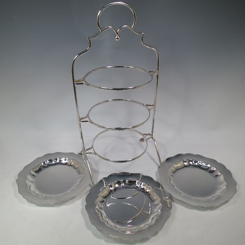 A pretty Antique Edwardian silver plated three-tier cake stand, having a suite of three plain removable plates with wavey-edged borders, sitting within a very pretty wire-work frame with scroll-work handle and four cast bun feet. Made in Sheffield in ca. 1910. The dimensions of this fine hand-made antique silver-plated cake stand are height 43 cms (17 inches), width at base 23 cms (9 inches), and diameter of plates 20 cms (8 inches).