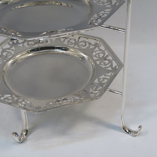 A very pretty Antique Edwardian silver plated three-tier cake stand, having a suite of three removable octagonal plates with hand-pierced scroll borders, sitting within a frame with four scroll-work feet. This beautiful antique silver-plated cake stand was made in ca. 1910. The dimensions of this fine hand-made antique silver-plated cake stand are height 41 cms (16 inches), width at feet 30.5 cms (12 inches), and diameter of plates 21.5 cms cms (8.5 inches).