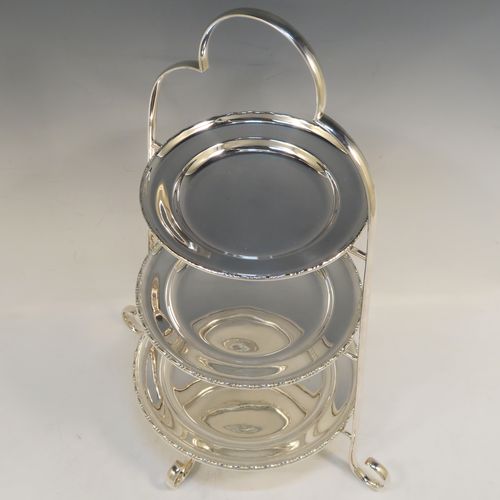 A very pretty Antique Edwardian silver plated three-tier cake stand, having a graduated suite of three removable round plates with applied egg and dart, sitting within a very handsome tapering frame with scroll-work handle and feet. This beautiful antique silver-plated three-tier cake stand was made in ca. 1910. The dimensions of this fine hand-made silver-plated cake stand are height 42 cms (16.5 inches), width at base 30.5 cms (12 inches), diameter of largest plate 20 cms (8 inches), and of of smallest plate 16 cms (6.3 inches).