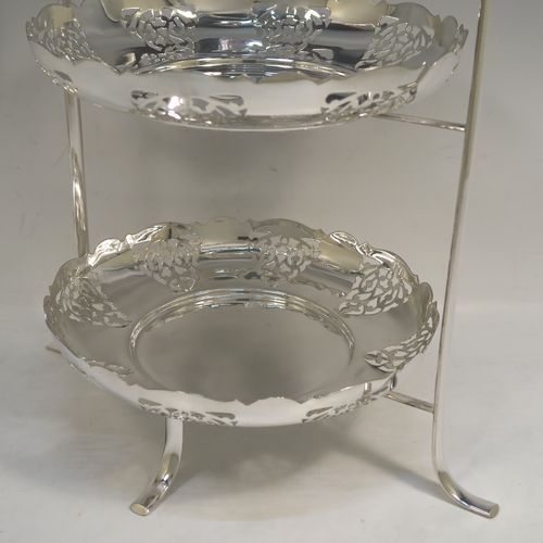 A pretty Antique Edwardian silver-plated cake stand, having two removable scalloped plates with round bodies and hand-pierced floral decoration. All sitting in a plain wire-work frame which in-turn sits on four scroll feet. This beautiful antique silver-plated cake stand was made in Sheffield ca. 1910. The dimensions of this fine hand-made antique silver-plated cake stand are height 36 cms (14.25 inches), width 30 cms (11.75 inches), and the plates are 21 cms (8.25 inches) square.