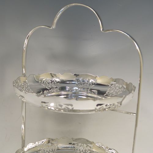 A pretty Antique Edwardian silver-plated cake stand, having two removable scalloped plates with round bodies and hand-pierced floral decoration. All sitting in a plain wire-work frame which in-turn sits on four scroll feet. This beautiful antique silver-plated cake stand was made in Sheffield ca. 1910. The dimensions of this fine hand-made antique silver-plated cake stand are height 36 cms (14.25 inches), width 30 cms (11.75 inches), and the plates are 21 cms (8.25 inches) square.