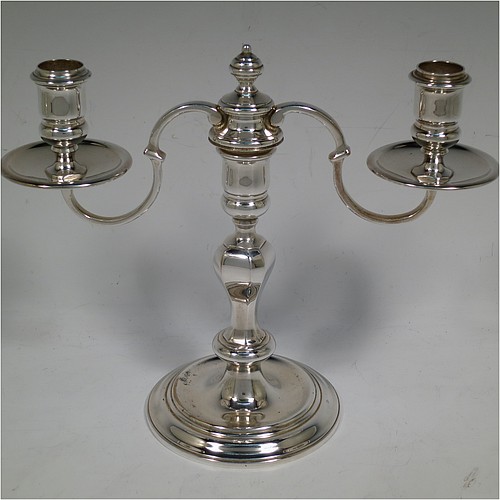A very handsome Silver Plated cast pair of George II style two-light candelabra, having octagonal panelled and round baluster style bodies with reeded borders, removable scroll arms with two-lights and drip pans, and a central finial. Made in circa 1930. The dimensions of this fine hand-made pair of silver-plated candelabra are height 19 cms (7.5 inches), and spread across arms 25.5 cms (10 inches).