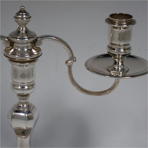 A very handsome Silver Plated cast pair of George II style two-light candelabra, having octagonal panelled and round baluster style bodies with reeded borders, removable scroll arms with two-lights and drip pans, and a central finial. Made in circa 1930. The dimensions of this fine hand-made pair of silver-plated candelabra are height 19 cms (7.5 inches), and spread across arms 25.5 cms (10 inches).