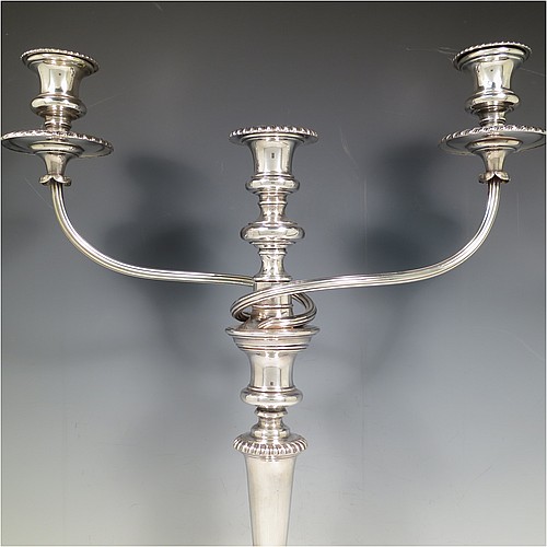 An Antique Georgian Old Sheffield Silver Plated pair of candelabra in a very elegant Regency style, having removable arms with three lights, with plain round baluster columns and bases, and plain reeded double swirl arms, removable nozzles with drip pans, and gadroon edged borders. Made in ca. 1815. The dimensions of this fine hand-made pair of Old Sheffield three-light candelabra are height 49 cms (19.25 inches), and spread across arms 39.5 cms (15.5 inches). Please note that the bases are crested.