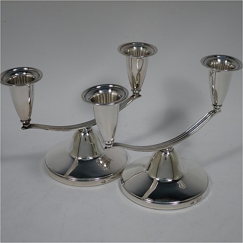 An unusual Sterling Silver pair of small two-light candelabra, having round bases with a cast reeded arms, with two attached plain round candle-holders. Made by Elkington and Co., of Birmingham in 1989. The dimensions of this fine hand-made pair of silver candelabra are height 11 cms (4.25 inches), and spread across arms 15 cms (6 inches).    