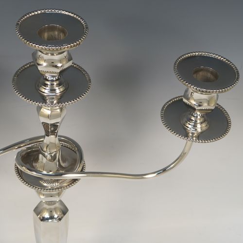 A very elegant pair of three-light Silver Plated Art Deco style candelabra, having plain hexagonal bases with an applied lower bead border, a plain panelled column with tapering sides, with removable swirl hexagonal cross-section arms, and matching capitals with removable nozzles and bead-edged borders. Made by Hawksworth and Eyre of Sheffield in ca. 1930. The dimensions of this fine hand-made pair silver-plated  Art Deco candelabra are height 40 cms (15.75 inches), and spread across arms 37 cms (14.5 inches).