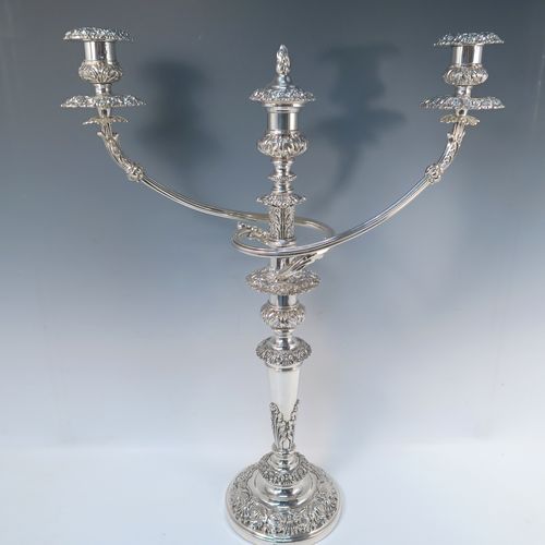 A large, bold, and very handsome pair of Antique Georgian Sterling Silver and Old Sheffield plated candelabra, having round baluster bodies with applied Regency style applied floral and scroll decoration, with removable three lights arms, original removable nozzles, drip pans, and flame extinguishers. The candelabra bases were made in Sterling Silver by Smith, Tate, Houle and Tate of Sheffield in 1822, whilst the original branches are made from Old Sheffield plate, which is quite a common combination from this period. The dimensions of this fine hand-made pair of antique silver candelabra are height 56 cms (22 inches), and spread across arms 43 cms (17 inches).